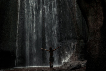 Uoung woman backpacker looking at the waterfall in jungles. Ecotourism concept image travel girl. Bali island, Indonesia.