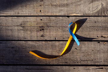 Blue and yellow ribbon as symbol of Down Syndrome Day on wooden background
