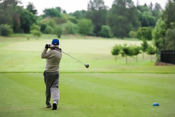 Man teeing off on a golf course with a driver