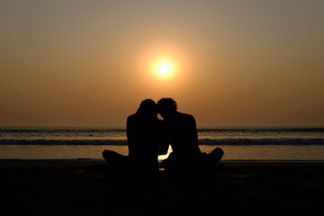 Couple's silhouette hugging on the beach at sunset