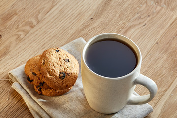 Porcelain teacup with chocolate chips cookies on cotton napkin on a rustic wooden background, top view