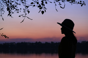 Silhouette of a young woman against beautiful purple color of evening sky 