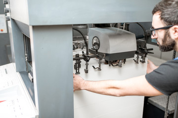 Worker filling up the paper sheets for printing into the offset printing machine at the manufacturing