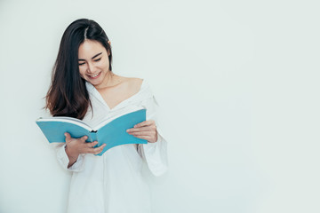 Asian girl who just wake up in the morning as relaxed. She reading the cyan book in isolated background.