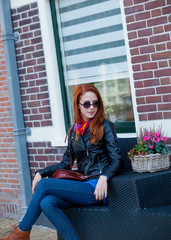 Fototapeta na wymiar Young girl in sunglasses sitting at chair near flowers