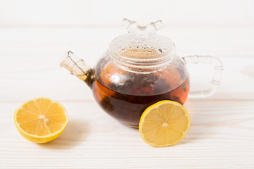 glass teapot with tea and lemon.hot vitamin c drink.white wooden table