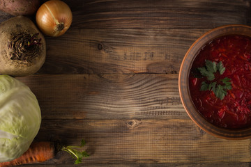 Borsch and its ingredients on a wooden background