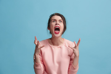 The young emotional angry woman screaming on blue studio background - Powered by Adobe