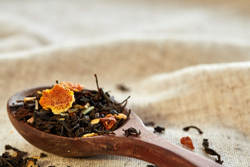 Closeup of a wooden spoon filled with scattered tea leaves, shallow depth of field, top view