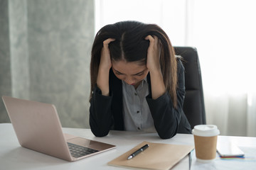 Young asian businesswoman feel stressed/worry/headache/disappoint during working while sit at office