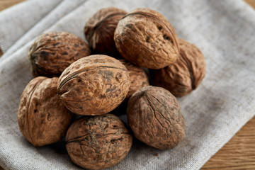 A stack of walnuts piled together and on rustic wooden background, shallow depth of field, selective focus