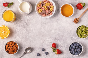 Breakfast with colorful cereal rings, fruit, milk, juice.