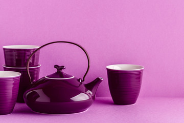 Purple teapot and cups on a lilac background