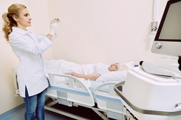 Obraz premium Supporting immune system. Positive minded medical worker checking a syringe while preparing for her senior patient vaccination.