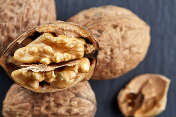 Top view close-up shot of cracked walnuts on dark background, shallow depth of field, macro