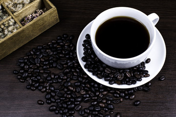 Black coffee in cup and coffee bean and box on wood background.