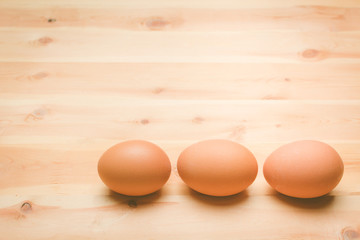 Three chicken eggs lie on a wooden board