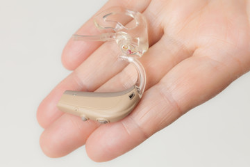 senior person holding hearing aid closeup
