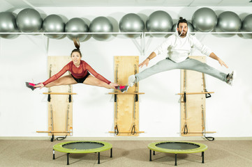 Young beautiful fitness couple workout extreme acrobatic exercise on trampoline jumps as...