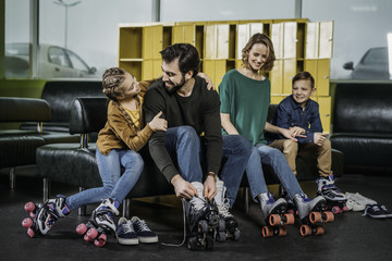 family resting on sofa before skating in roller skates in skate park