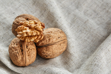 A stack of hard shells of walnuts piled together on light grey fabric cotton tablecloth, selective focus