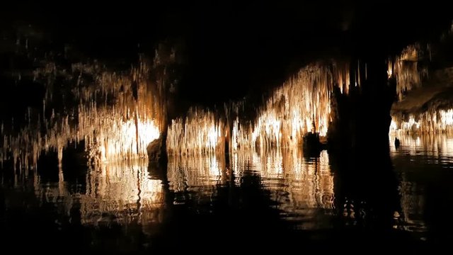 MAJORCA, SPAIN Tourists float on a boat on the underground lake in the famous stalactite caves of Dragon (Cuevas del Drach)