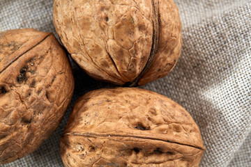 A stack of hard shells of walnuts piled together on light grey fabric cotton tablecloth, selective focus