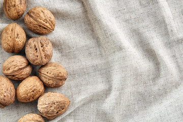 A stack of hard shells of walnuts piled together on light grey fabric cotton tablecloth, selective focus