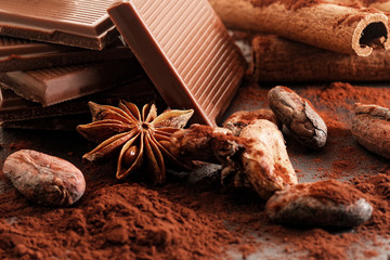 Broken dark chocolate, cocoa powder and coffee beans on a wooden table