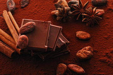 Broken dark chocolate, cocoa powder and coffee beans on a wooden table