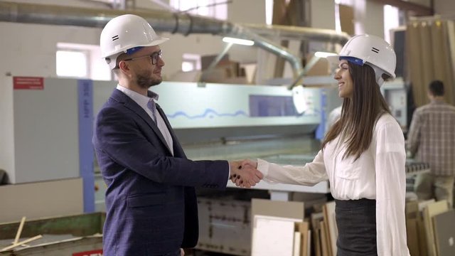 Portrait of satisfied business man and woman shaking hands, as making deal on furniture manufacture slow motion