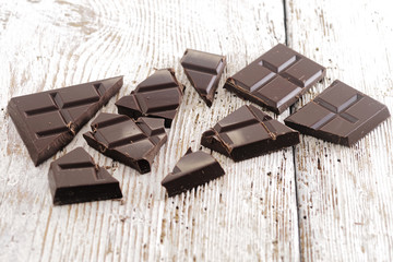 Broken dark chocolate, cocoa powder and coffee beans on a wooden table
