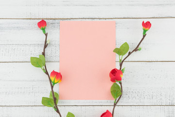 Blank pink cards decorated with fake red flower branches on white wood background 
