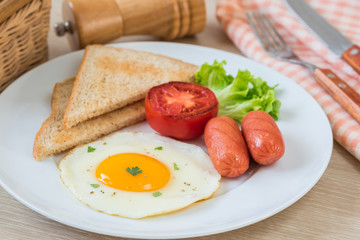 Fototapeta na wymiar Breakfast with fried egg, toast, sausage and vegetable on plate
