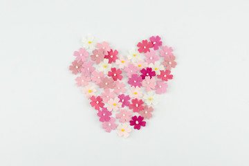 Heart shape made from pink paper flowers on white background 