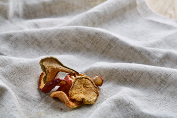 Top view close-up picture of dried apples on light cotton tablecloth, selective focus.