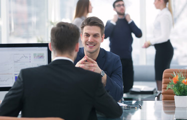 Two men discuss the growth of the company, looking at the rising graph on a computer screen