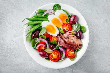 nicoise salad with tuna, anchovies, eggs, green beans, olives, tomatoes, red onions and salad leaves