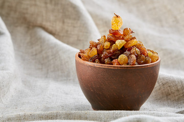 Ceramic bowl with golden raisins on light tablecloth, close-up, selective focus