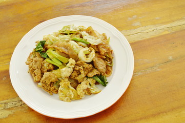 fried large rice noodles with pork and vegetable in black soy sauce on plate