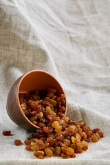 Ceramic bowl with golden raisins on light tablecloth, close-up, selective focus