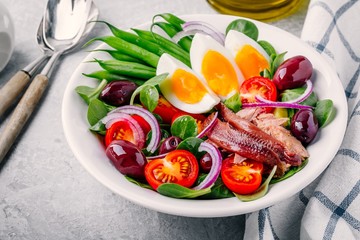 nicoise salad with tuna, anchovies, eggs, green beans, olives, tomatoes, red onions and salad leaves