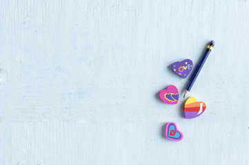 different  eraser in the shape of a heart with a pencil on blue background with space for text