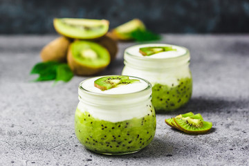 Obraz na płótnie Canvas Kiwi jam and yogurt parfait in glass jars on concrete background. Selective focus, copy space. 