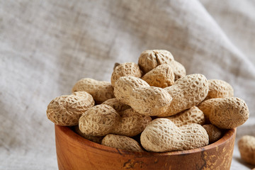 Unpeeled peanuts in ceramic bowl closeup, selective focus