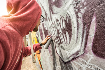 Street artist painting colorful graffiti on public wall - Modern art concept with urban guy...