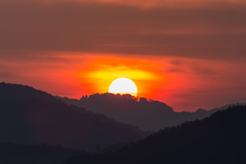 Fototapeta na wymiar Beautiful landscape of a big setting sun over the silhouette of the mountains, Salciua, Romania