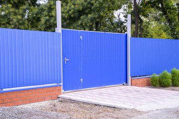 Fence and gate from sheets of blue corrugated metal.