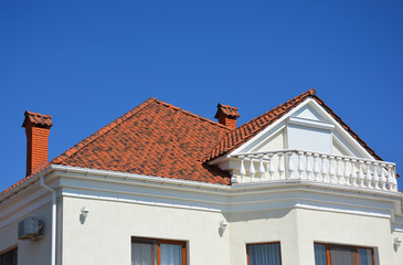 Luxury roofing constraction with natural clay roof tiles, house attic balcony and metal shutters, blinds.