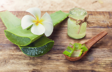 Aloe vera gel and Aloe leaf cut pieces on a wooden background